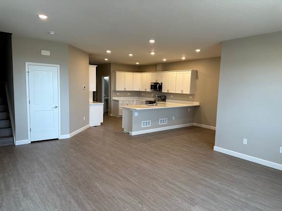 an empty living room and kitchen with a wooden floor