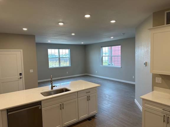 an empty kitchen with white cabinets and a sink