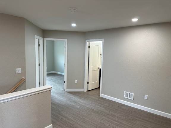 an empty living room with a hallway and a door to a bedroom