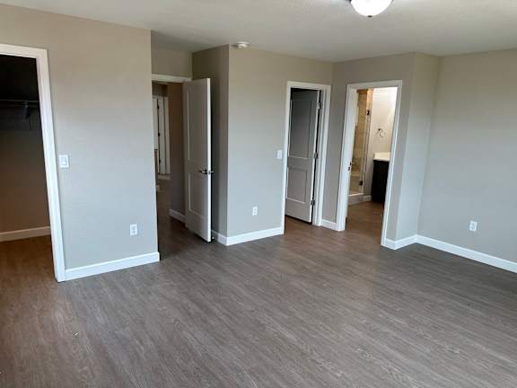 an empty living room with wood flooring and a hallway