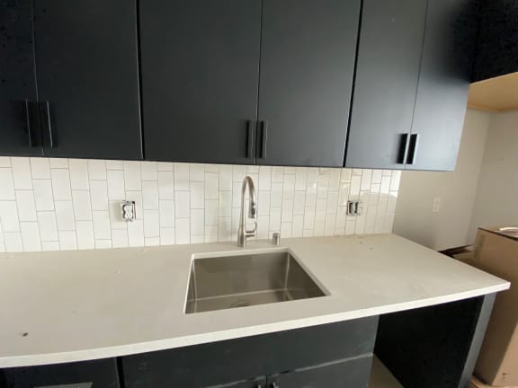 a picture of a kitchen with white tile and black cabinets
