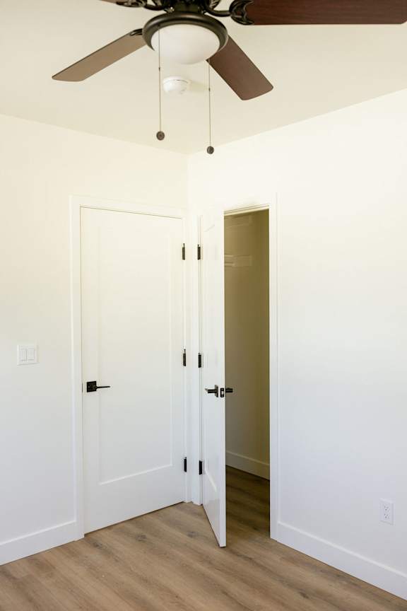 A room with a ceiling fan and two doors.