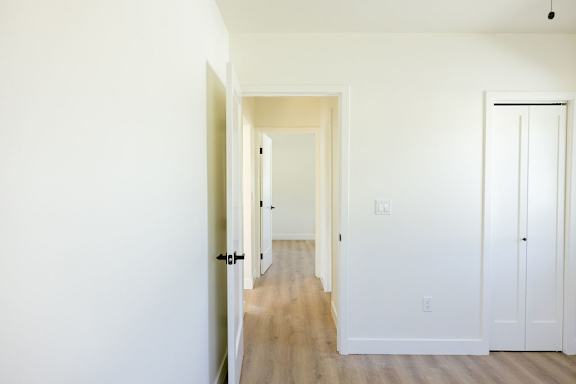 A long hallway with white walls and wood floors.