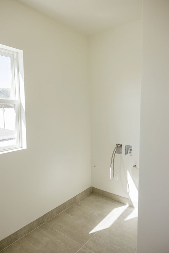 A bathroom with a white wall and a window.