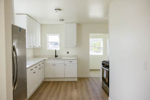 A kitchen with white cabinets and a stainless steel refrigerator.