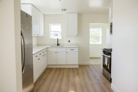 A kitchen with white cabinets and a stainless steel refrigerator.