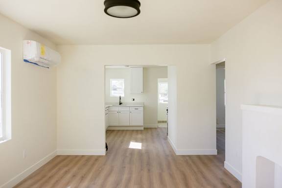 A room with a white cabinet and a window with an air conditioner on the wall.