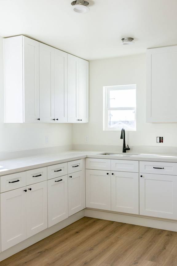 A kitchen with white cabinets and a window.