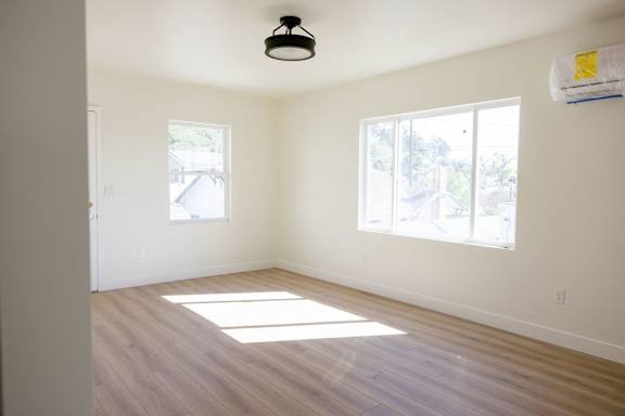 A room with a light on the ceiling and two windows letting in sunlight.