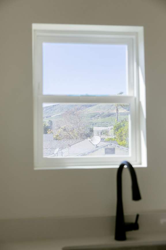 A kitchen sink with a window overlooking a residential area.