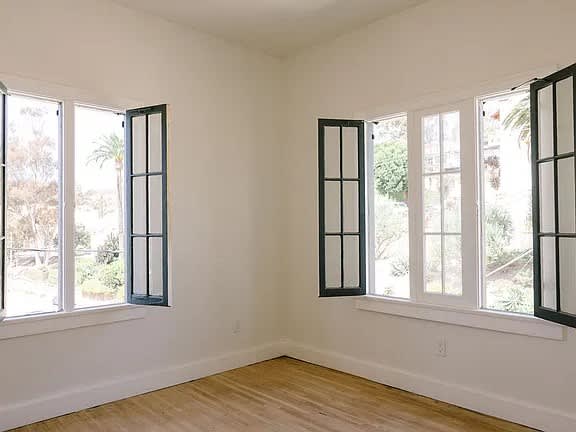 A room with two windows and wooden flooring.