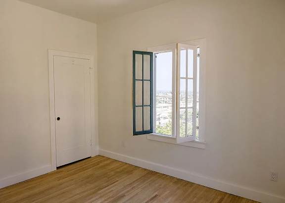 A room with a white door and a window with a view of the street.
