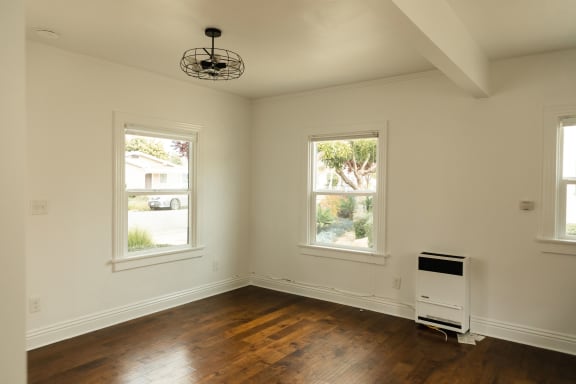 an empty room with three windows and a chandelier