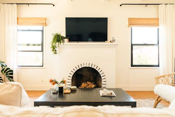 A living room with a fireplace and a flat screen TV mounted above it.