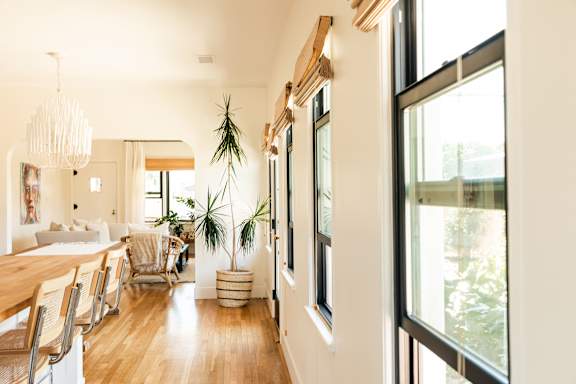 A long hallway with a table and chairs on the left and a plant in a pot on the right.