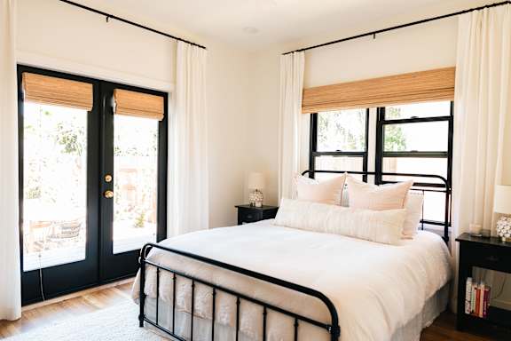 A bedroom with a large bed and a sliding glass door.