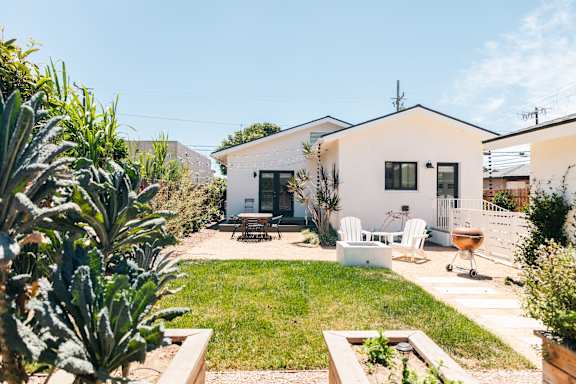 A white house with a patio and a garden in front.