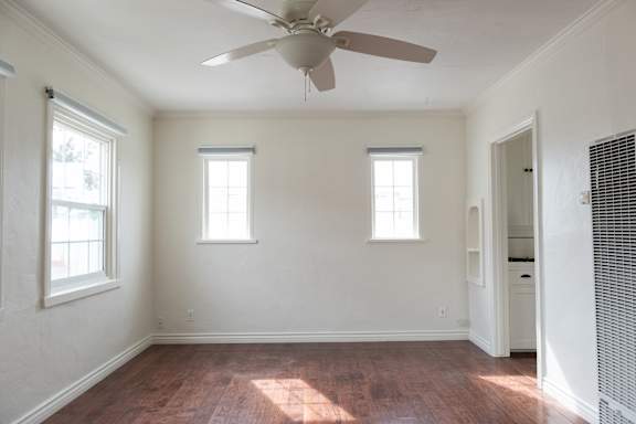 an empty room with a ceiling fan and two windows