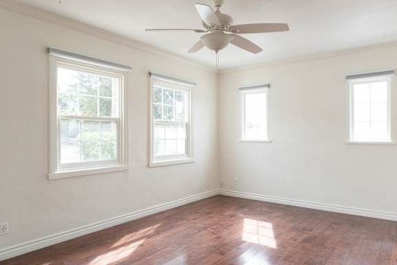 an empty room with a ceiling fan and three windows