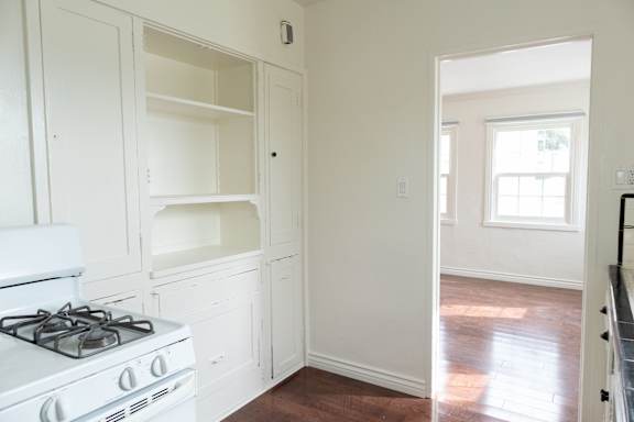 a kitchen with white cabinets and a stove and a window