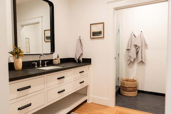 A bathroom with a black counter top and white cabinets.