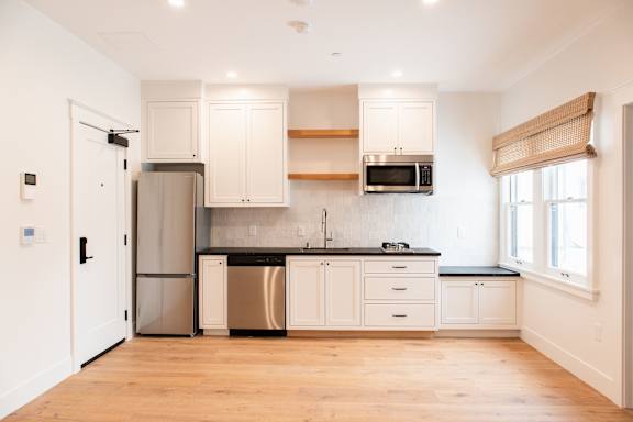 A kitchen with white cabinets and a black countertop.