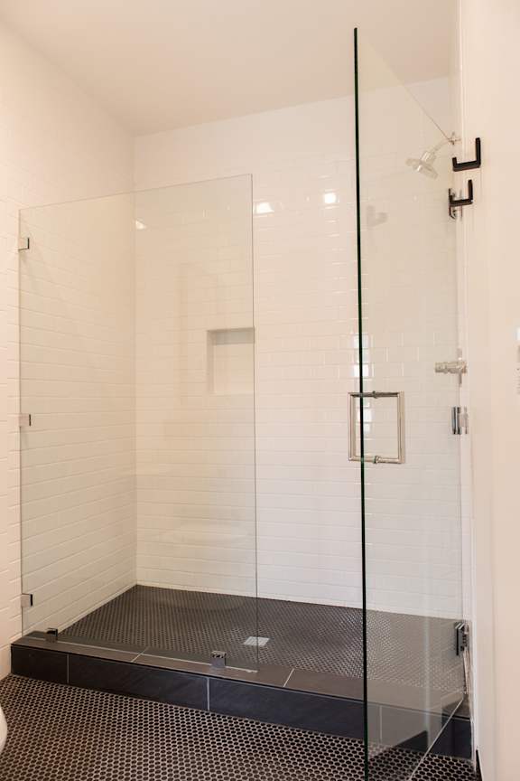 A glass shower stall with a black mat on the floor.