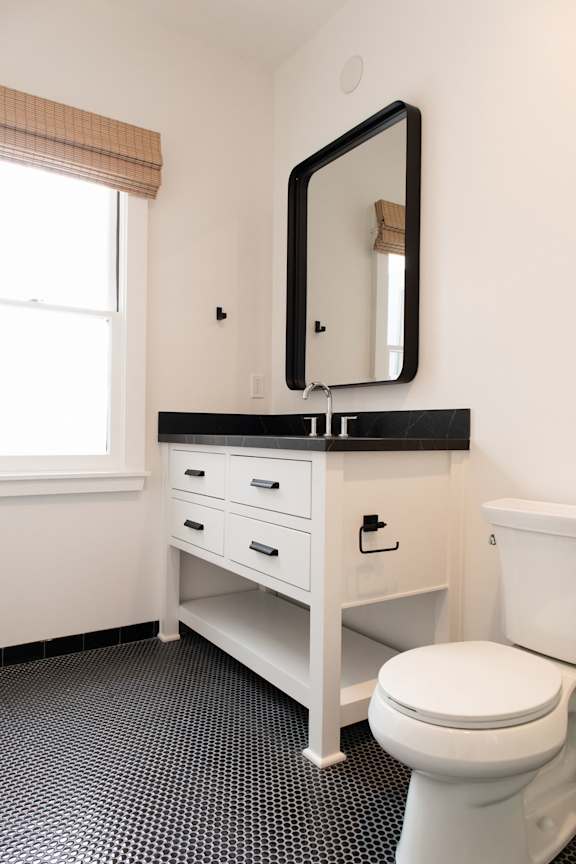 A white toilet sits under a mirror in a bathroom.