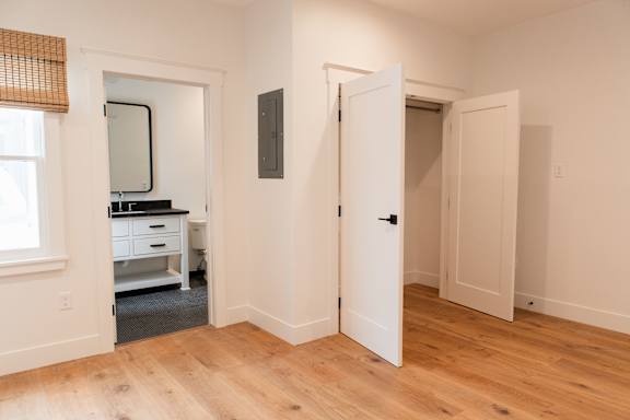 A room with a white door and a mirror on the wall.