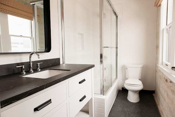 A white toilet sits in a bathroom next to a sink and a shower.
