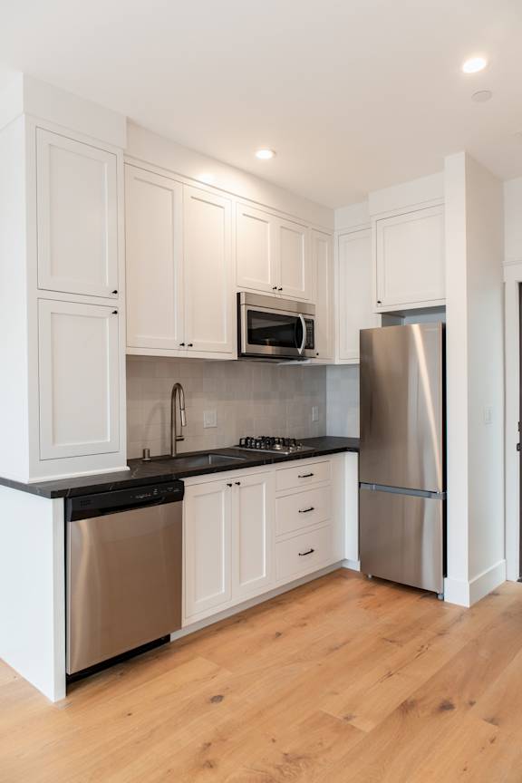 A kitchen with white cabinets and a black countertop.