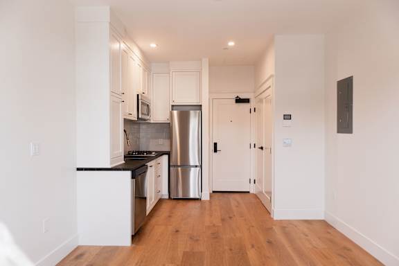 A kitchen with white cabinets and a stainless steel refrigerator.