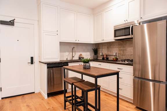 A kitchen with white cabinets and a wooden table.