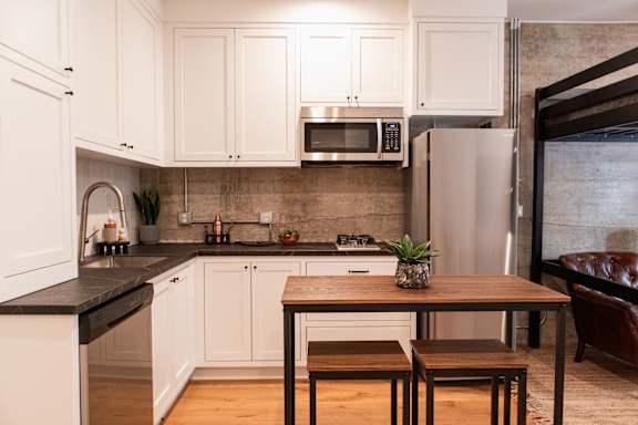 A kitchen with white cabinets and a black countertop.