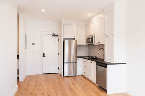 A kitchen with white cabinets and a black countertop.