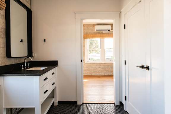 A bathroom with a sink, mirror, and a door.