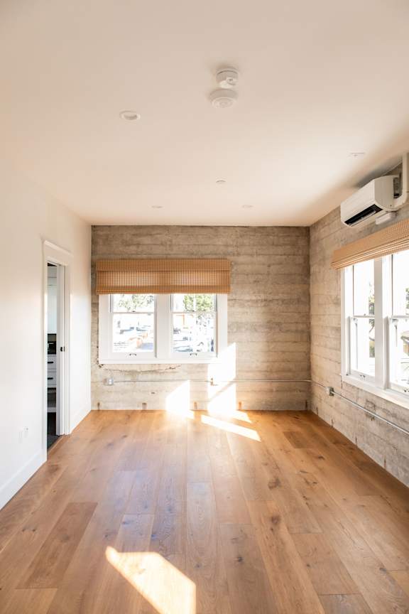 A room with wooden floors and a window with blinds.
