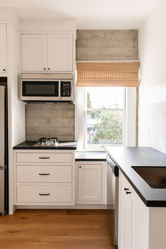A kitchen with white cabinets and black countertops.