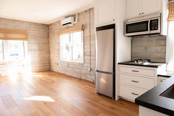 A kitchen with wooden floors and a stainless steel refrigerator.