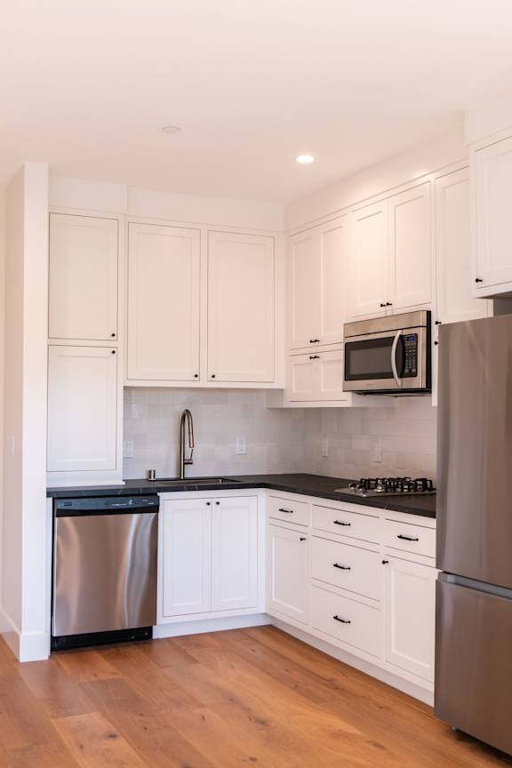 A kitchen with white cabinets and a stainless steel refrigerator.