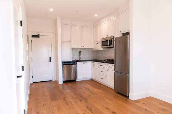 A kitchen with white cabinets and a wooden floor.