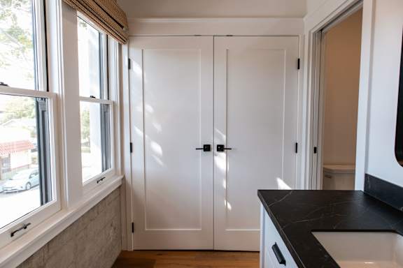 A kitchen with white cupboards and a black counter top.
