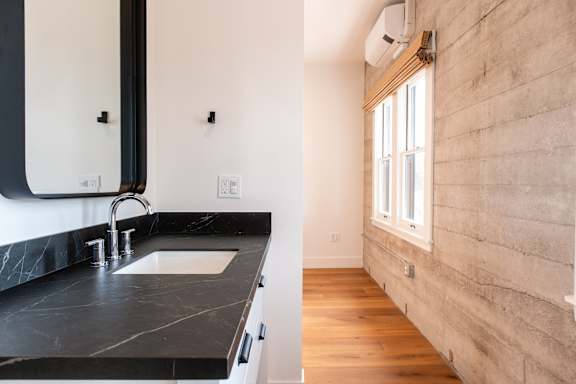 A modern bathroom with a black marble countertop and a wooden wall.