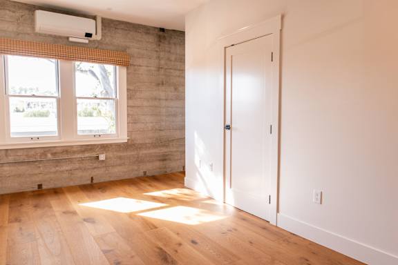 A room with a wooden floor and a window with blinds.