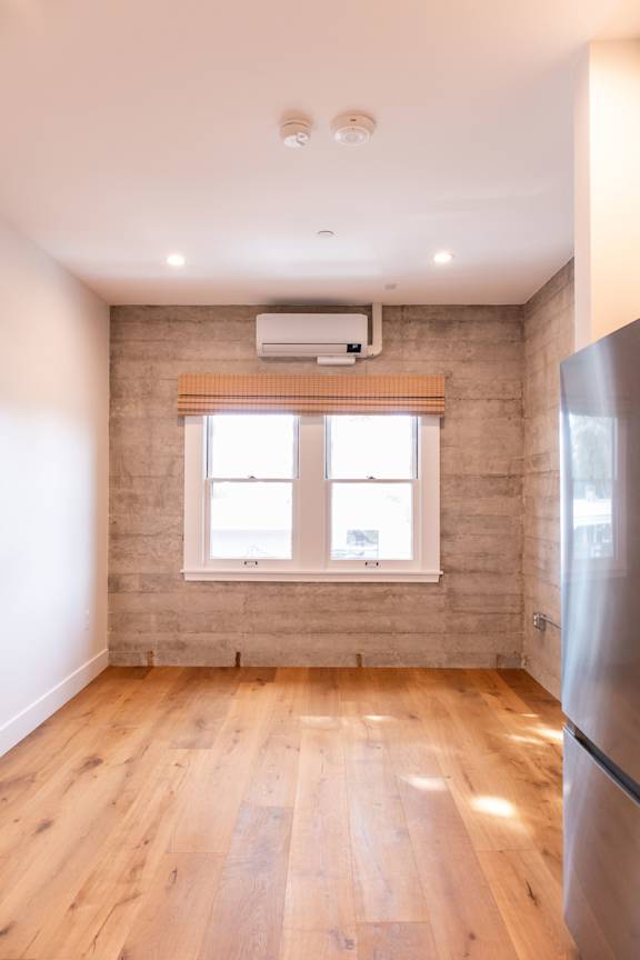 A room with wooden floors and a window with a curtain.