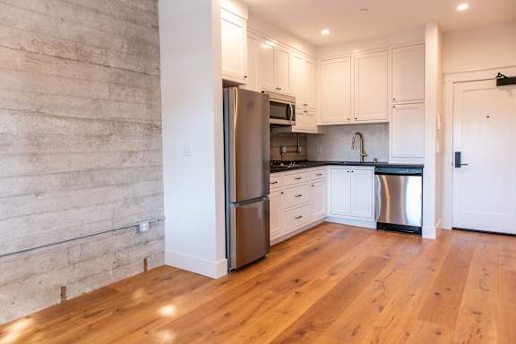 A kitchen with a refrigerator, microwave, and oven.
