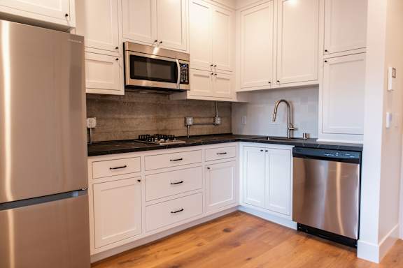A kitchen with white cabinets and a stainless steel refrigerator.