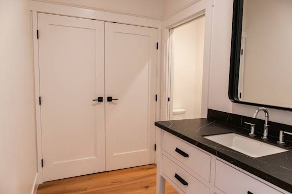 A bathroom with a sink, mirror, and cabinets.