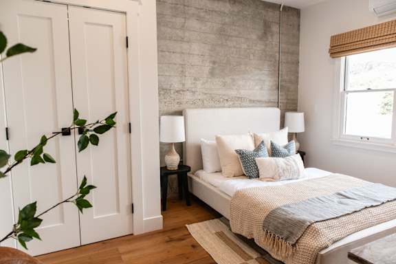 A bedroom with a bed, nightstand, and a plant.