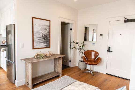 A room with a chair and a table with a plant on it.